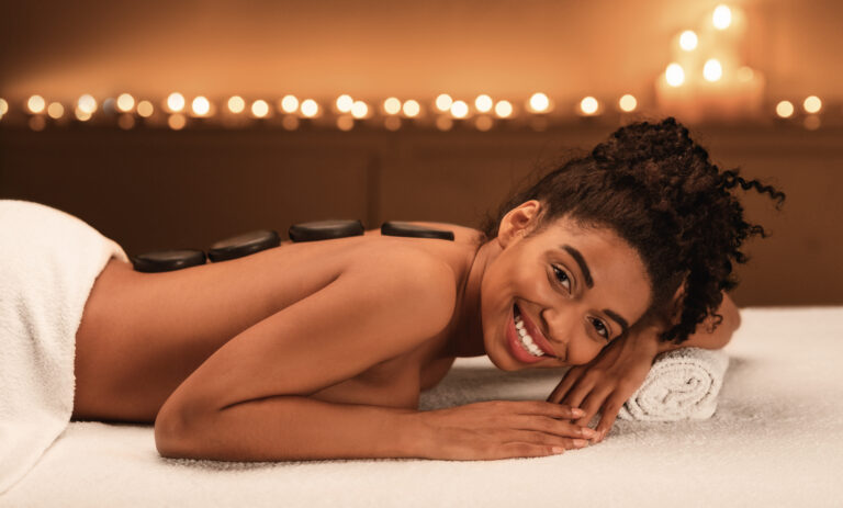 Happy african american woman enjoying hot stone massage at spa